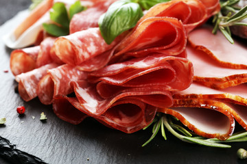 Marble cutting board with prosciutto, bacon, salami and sausages on wooden background. Rustic Meat platter