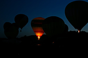 People in basket of hot air balloon in the background of sunset. Burner heating gas and inflating...