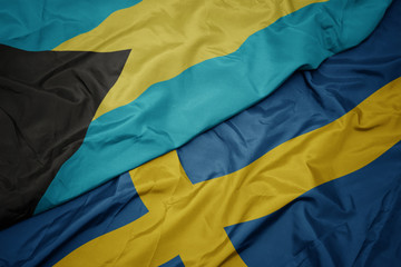 waving colorful flag of sweden and national flag of bahamas.