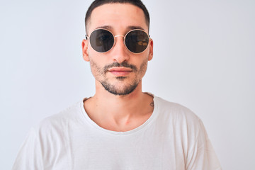 Young handsome man wearing sunglasses and casual t-shirt over isolated background with a confident expression on smart face thinking serious