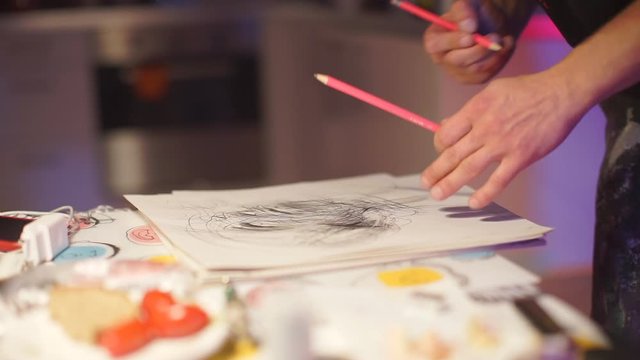 the artist draws a picture with pencils on paper