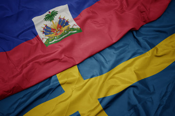 waving colorful flag of sweden and national flag of haiti.