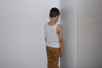punished for a bad deed the boy stands in the corner, his back, educational concept - obrazy, fototapety, plakaty