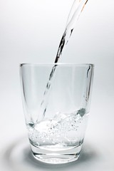 pouring water into glass isolated on white