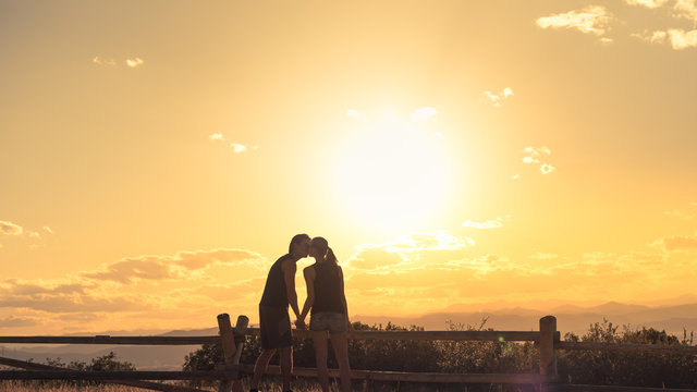 Couple kissing in a beautiful nature sunset setting. Romantic getaway concept. 