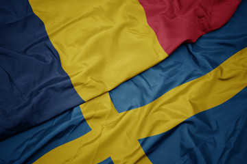 waving colorful flag of sweden and national flag of chad.