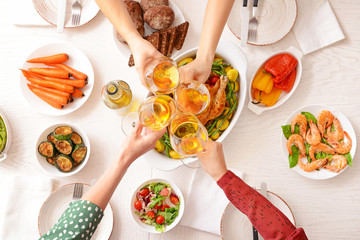 Friends clinking glasses with wine during dinner, top view
