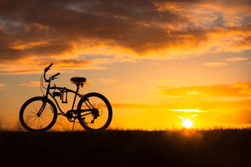 Fototapeta na wymiar Silhouette of bicycle on field at sunset. 