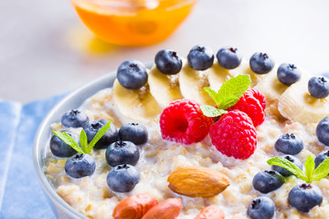 Healthy homemade oatmeal with berries and nuts for breakfast. Oatmeal with fruits, nuts and honey. Oatmeal with blueberries, banana and raspberries