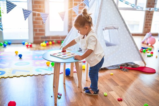 Young beautiful toddler learning mathematics playing with maths game at kindergaten