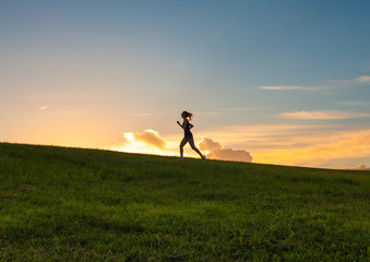 Female running up hill at sunset. 