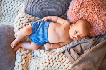 Adorable baby lying down on the sofa over blanket at home. Newborn relaxing and resting comfortable