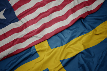 waving colorful flag of sweden and national flag of liberia.
