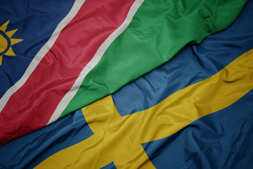 waving colorful flag of sweden and national flag of namibia.