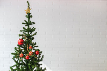 Fototapeta na wymiar christmas tree with ornaments on white brick wall background