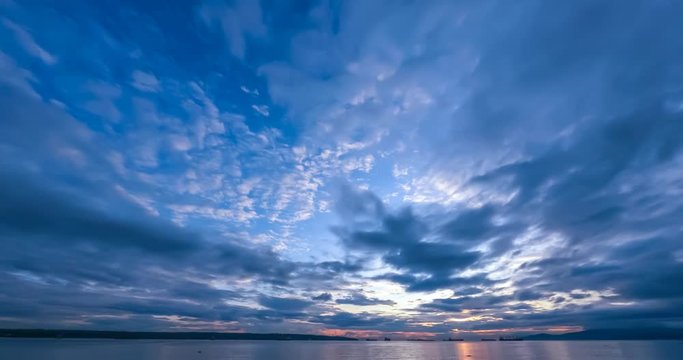 Time-lapse video panorama of the sunset over the ocean. Clouds running across the sky, the silhouette of forest and ships on a summer evening