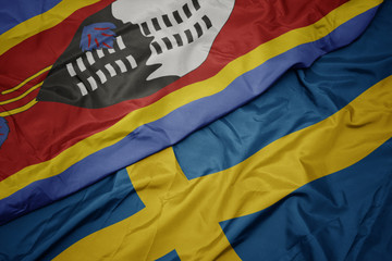 waving colorful flag of sweden and national flag of swaziland.