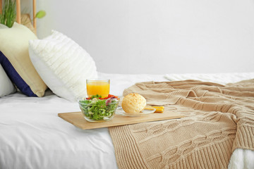 Tray with tasty breakfast on bed