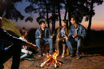 Young friends spending weekend in forest at night