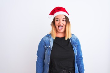Young beautiful woman wearing Christmas Santa hat standing over isolated white background sticking tongue out happy with funny expression. Emotion concept.