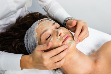 Beautiful woman receiving natural green peel facial mask with rejuvenating effects in spa beauty salon. - 295957083