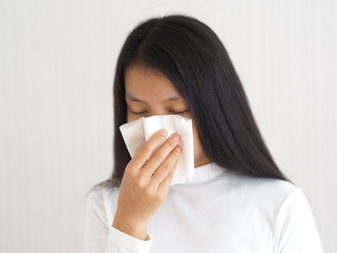 common cold and flu or influenza epstein barr virus or EBV and sinusitis, nasal polyp and asthma in woman and she hold white paper napkin close on nose on white background use for health care concept.