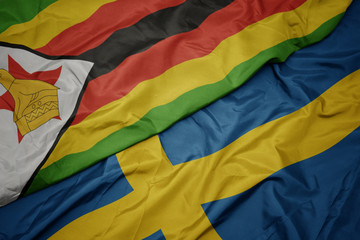 waving colorful flag of sweden and national flag of zimbabwe.