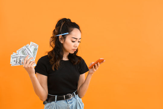 Sad Asian Woman With Money And Calculator On Color Background