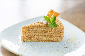 Honey sponge cake decorated with meringue and mint leaves. Breakfast in the cafe, morning coffee. on wooden table. Restaurant menu