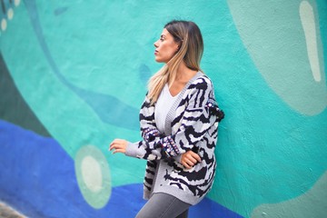 Young beautiful girl smiling happy and confident leaning on the wall at the town street, standing with a smile on face