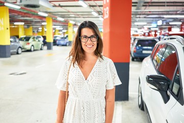 Young woman smiling confident at underground parking lot around cars and lights