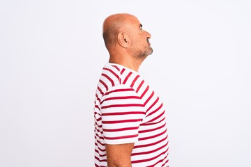 Middle age handsome man wearing striped t-shirt standing over isolated white background looking to side, relax profile pose with natural face with confident smile.