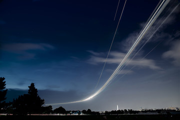 light trails of an ariplane with the washington monument in the background