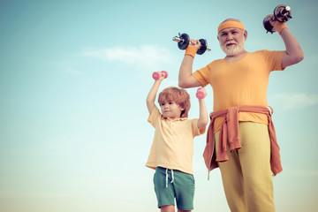 Old mature man and little boy exercising with dumbbell. Body care and healthcare. Cute kid and...