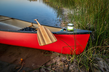 red canoe with lantern on a lake shore