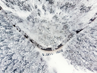 Beautiful aerial view of snow covered pine forests and a road winding among trees. Rime ice and hoar frost covering trees. Scenic winter landscape in Vilnius, Lithuania.