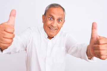 Senior grey-haired man wearing elegant shirt standing over isolated white background approving doing positive gesture with hand, thumbs up smiling and happy for success. Winner gesture.