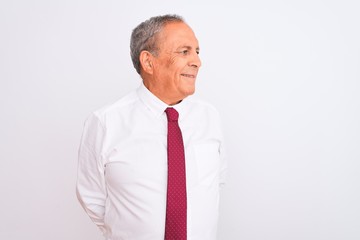 Senior grey-haired businessman wearing elegant tie over isolated white background looking away to side with smile on face, natural expression. Laughing confident.