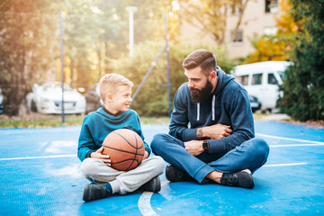 Fototapeta na wymiar Father and his son enjoying together on basketball court.
