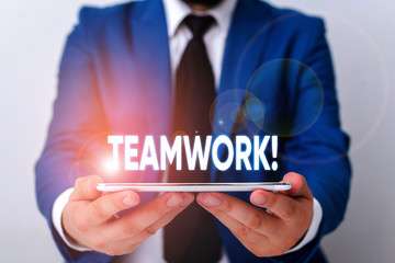 Handwriting text writing Teamwork. Conceptual photo combined action of group especially when effective and efficient Businessman in blue suite with a tie holds lap top in hands