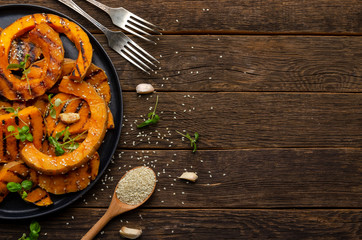 roasted pumpkin slices on old wooden background. Healthy vegetarian, vegan food.