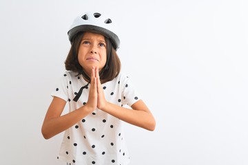 Beautiful child girl wearing security bike helmet standing over isolated white background begging and praying with hands together with hope expression on face very emotional and worried