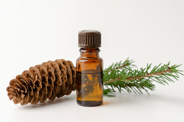 bottle of fir tree essential oil on white with pine cone