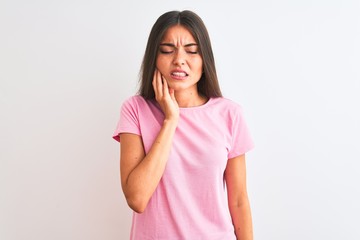 Young beautiful woman wearing pink casual t-shirt standing over isolated white background touching mouth with hand with painful expression because of toothache or dental illness on teeth