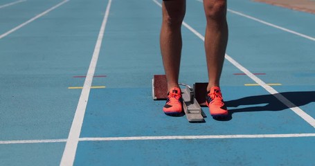 Athletics Runner ready to run on running track start line in starting blocks. Sport athlete going sprinting towards success on blue tracks. Sprinter on competition race challenge at stadium.