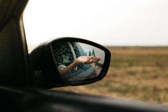 Hand touching rain drops. Mirror seen through the glass. Wet car window. Close up rain drop. Car view see the mirror. Rainy day. © EGHStock