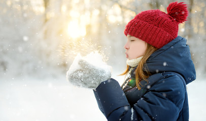 Adorable young girl having fun in beautiful winter park. Cute child playing in a snow. Winter activities for family with kids.