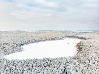 Beautiful aerial view of snow covered pine forests aroung Gela lake. Rime ice and hoar frost covering trees. Scenic landscape near Vilnius, Lithuania.
