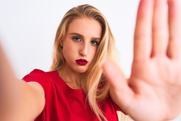 Young beautiful woman wearing t-shirt make selfie by camera over isolated white background with...