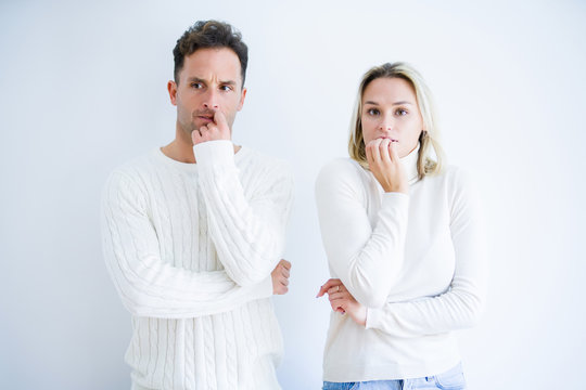 Young beautiful couple wearing casual t-shirt standing over isolated white background looking stressed and nervous with hands on mouth biting nails. Anxiety problem.